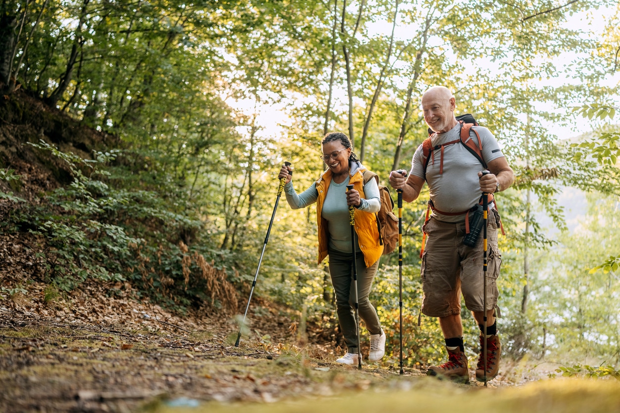 Hiking Couple Trekking Through a Lush Forest Trail With Backpacks and Poles