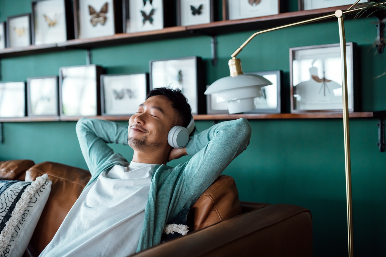 Man relaxing on the couch listening to music from his headphones